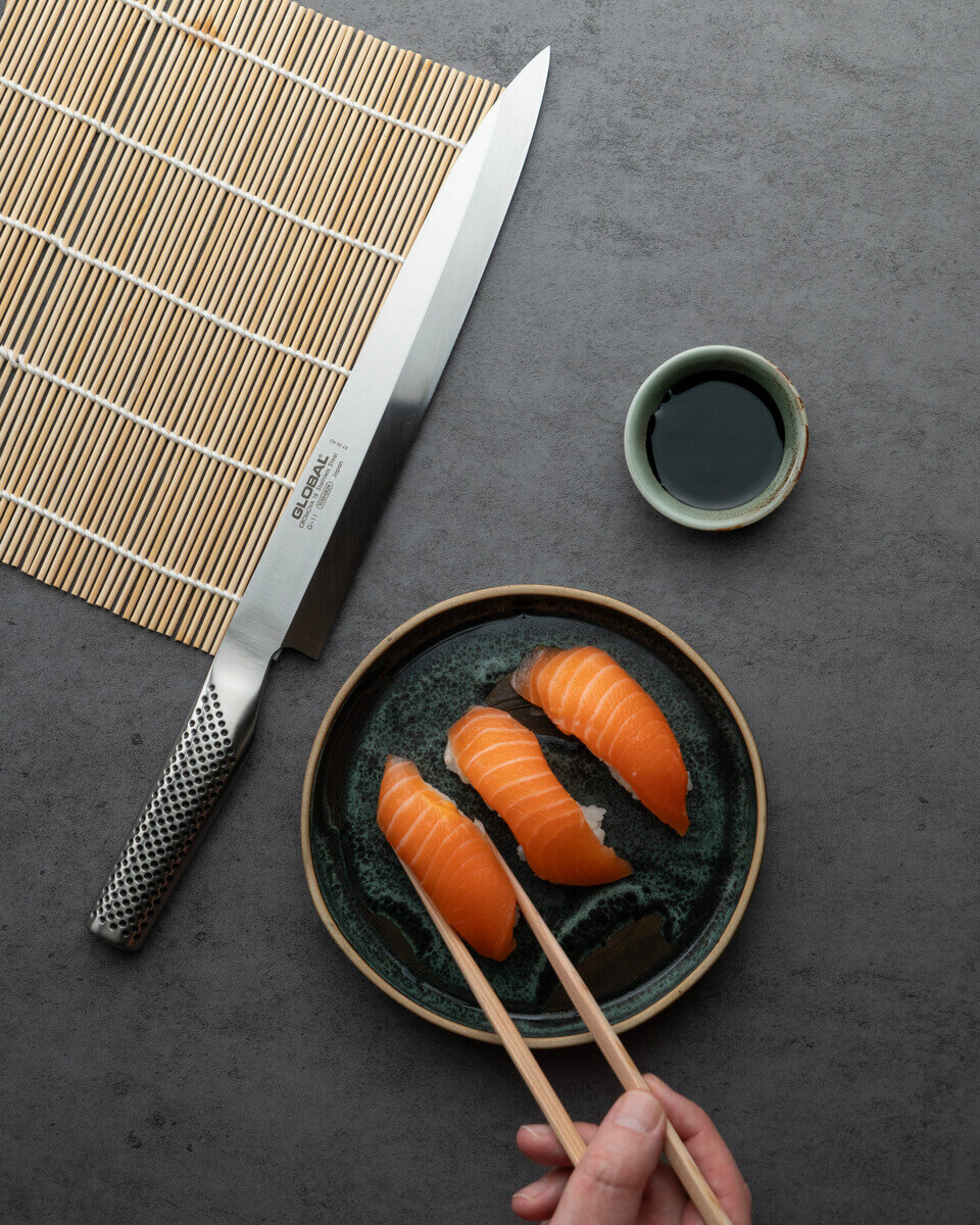 Een Global yanagi-mes naast een bord sushi